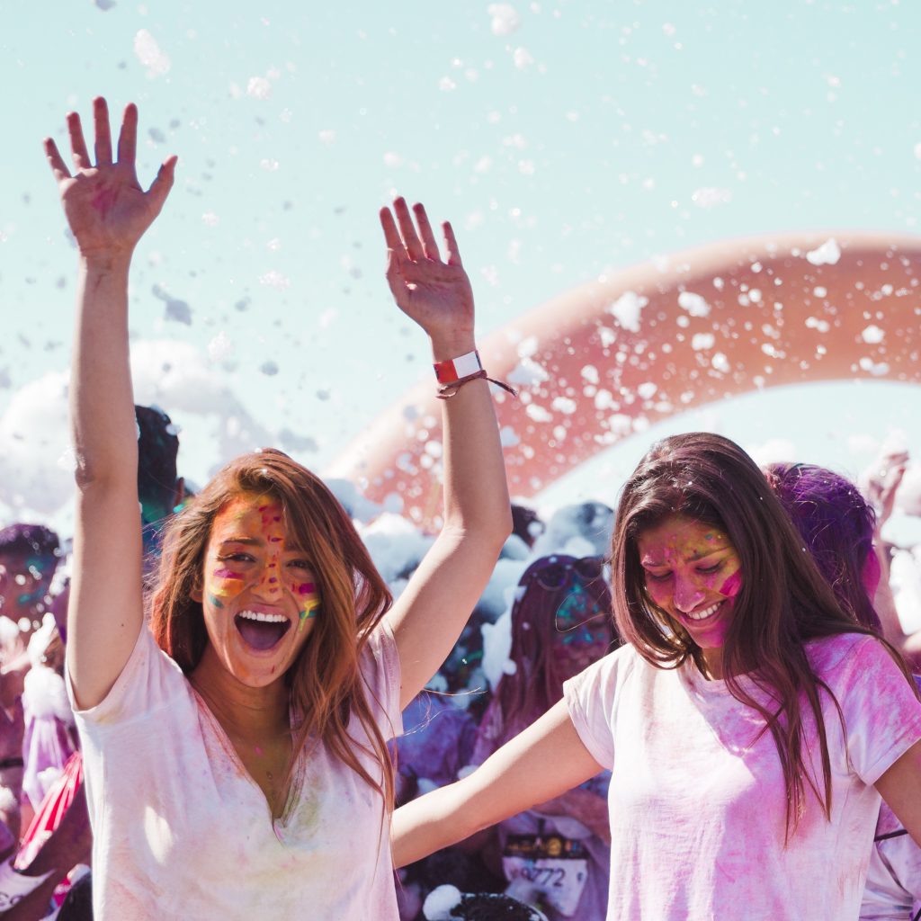 Jeunes femmes souriantes couvertes de poudres colorées lors d’un festival – illustration d’une vidéo événementielle dynamique, produite dans le cadre des services de montage vidéo à Lorient proposés par Keltic Prod